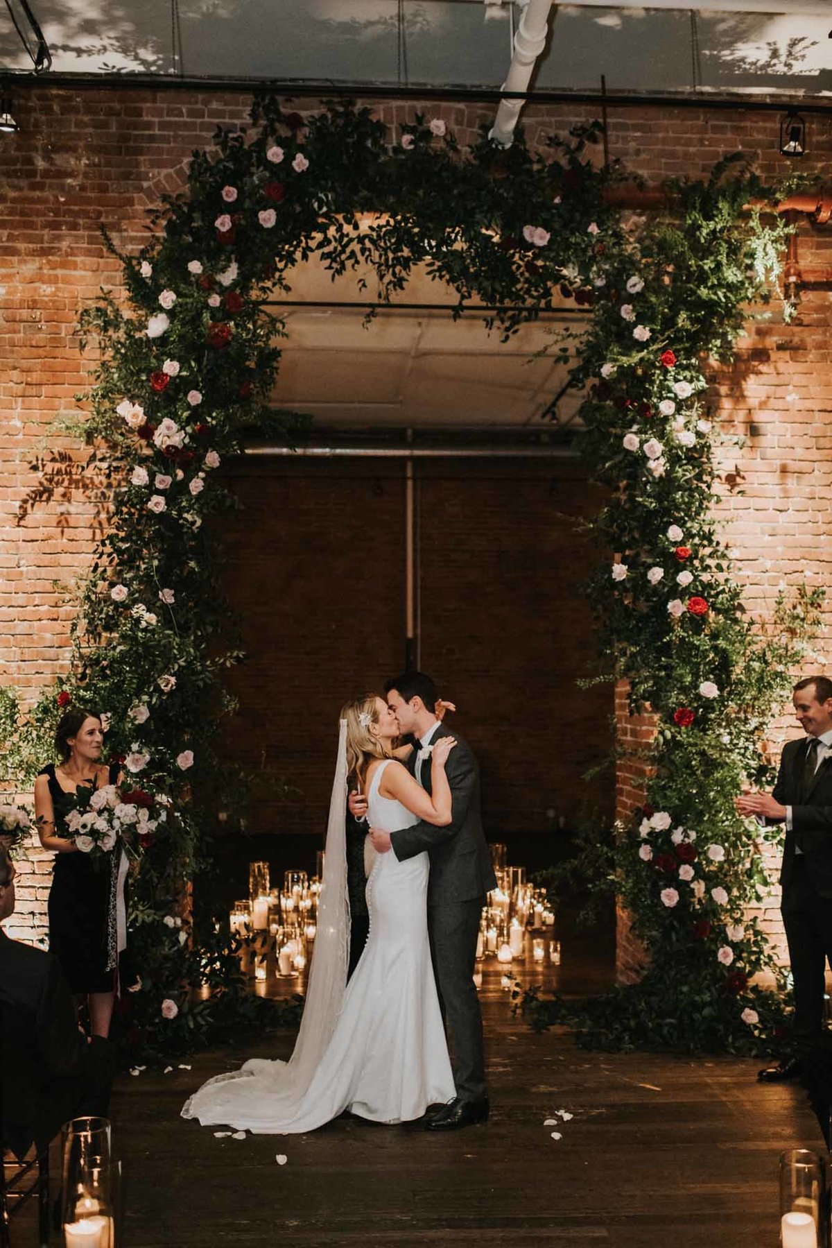 bride and groom's first kiss at Axis Pioneer Square wedding with extra tall greenery arbor