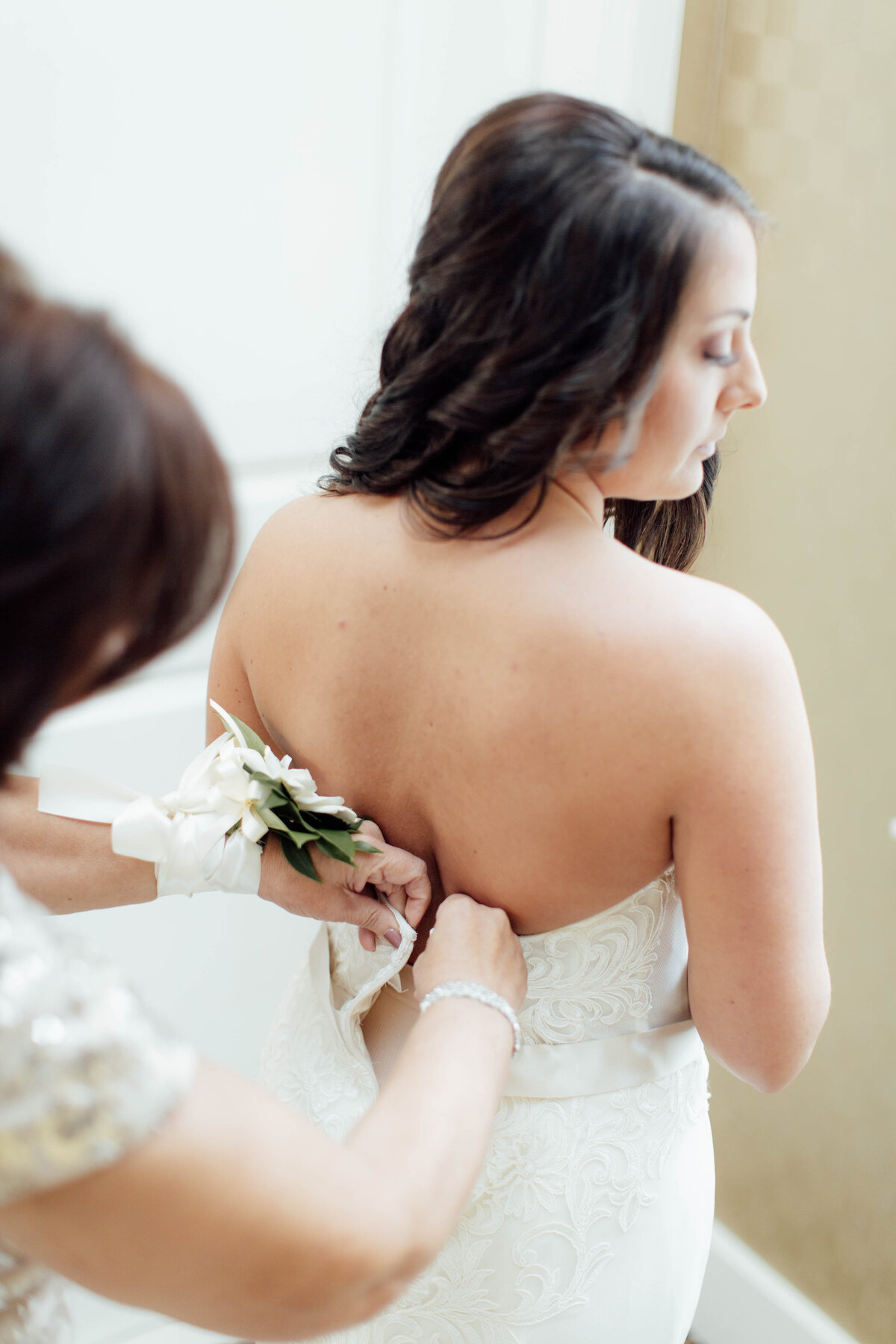 Mother of bride helping put wedding dress on.
