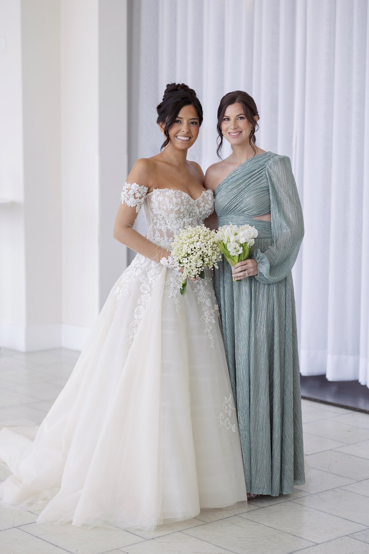 Bride poses with Bridesmaid in teal dress at Belle Mer Newport.