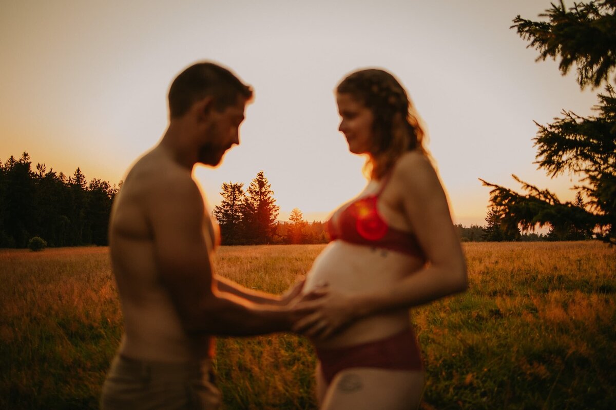 photo grossesse homme posant ses mains sur ventre de la femme au coucher du soleil en montagne