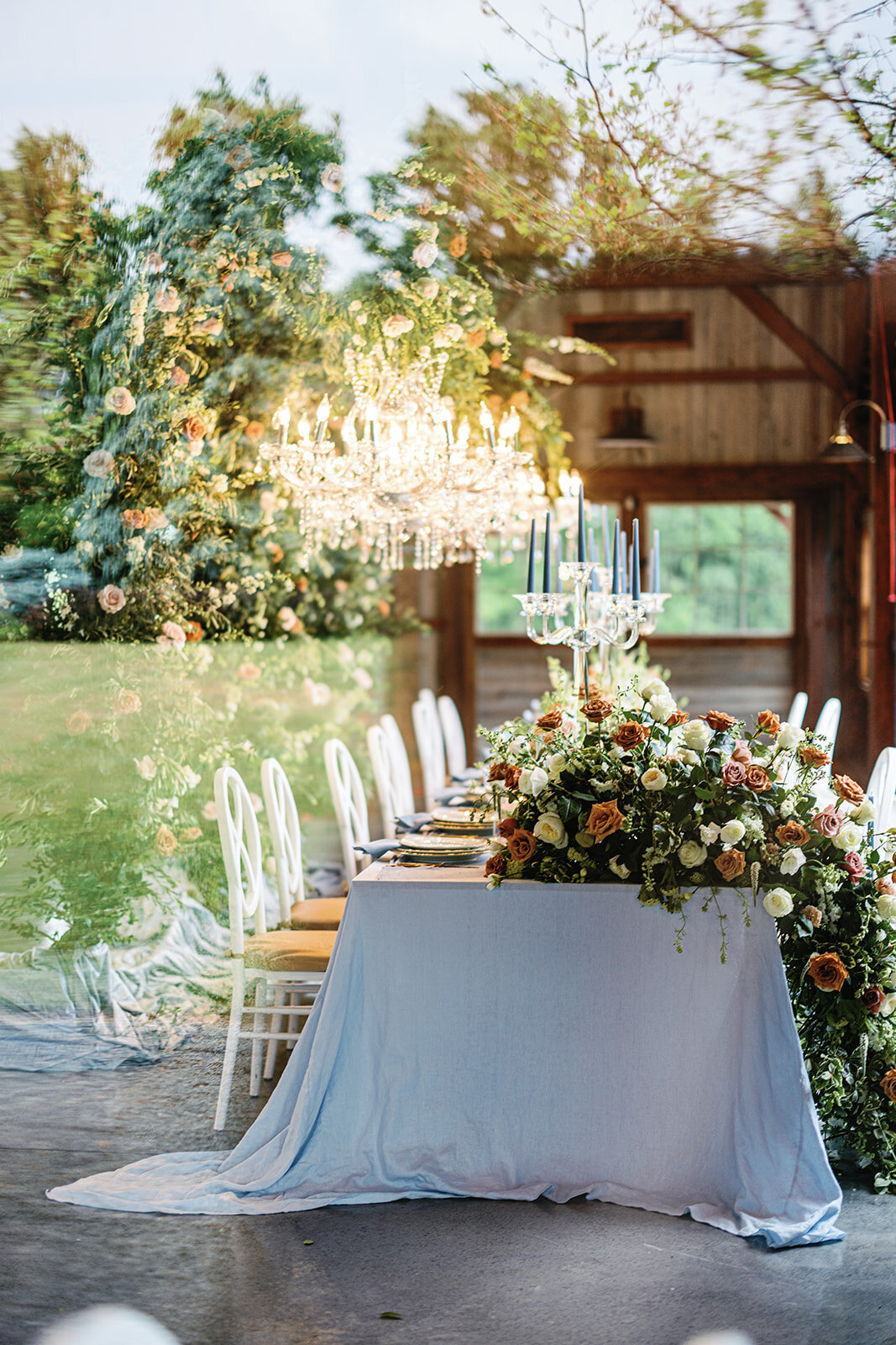 Table with long white tablecloth and large orange and green floral centerpieces