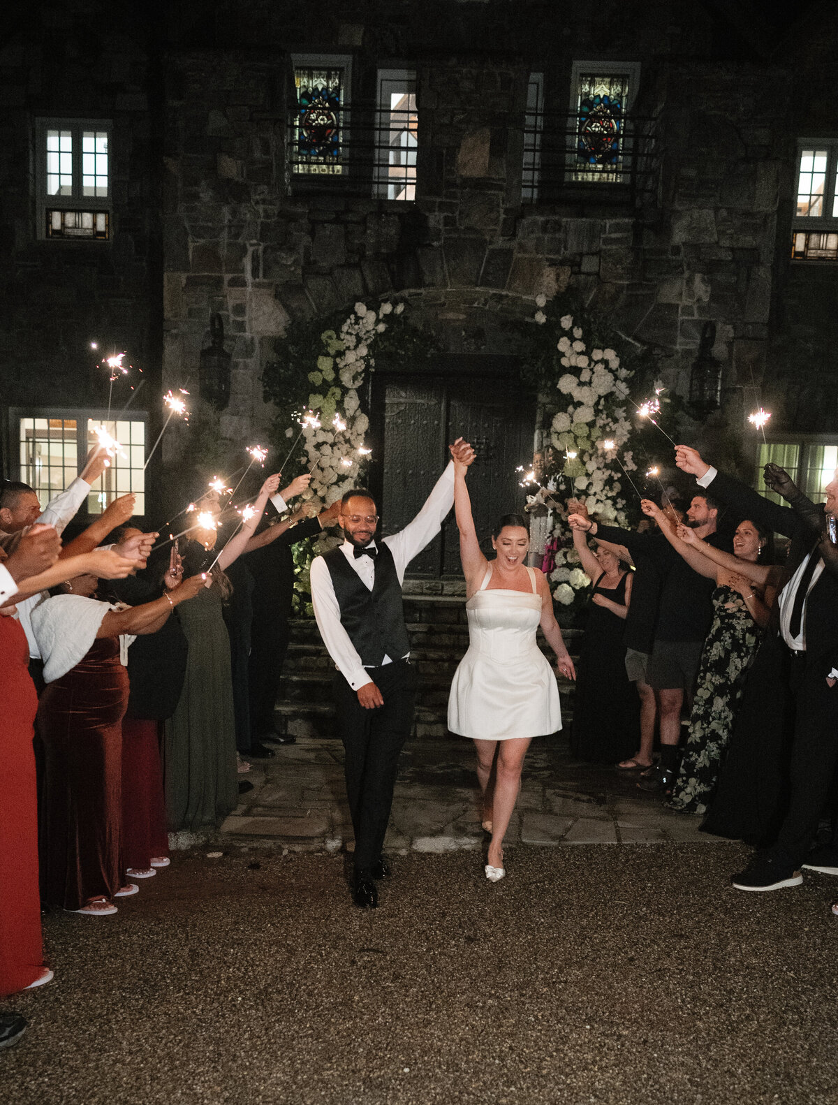 The bride and groom make a celebratory sparkler exit outside Castle Ladyhawke at their fall mountain wedding.