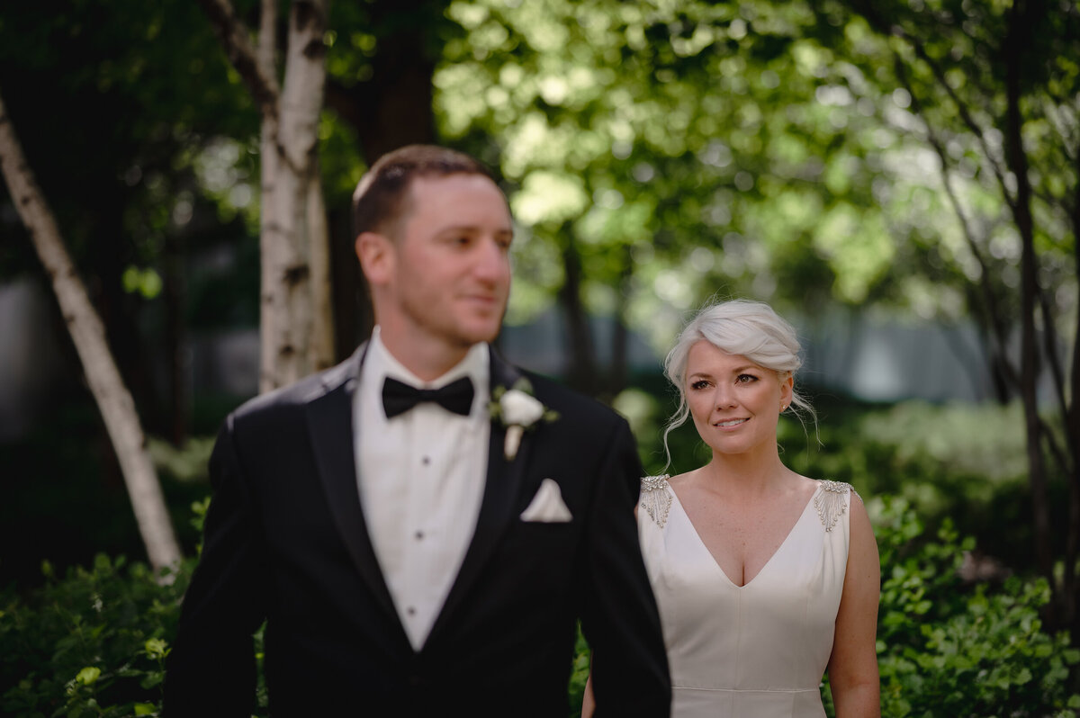 A bride with short hair looks at her groom in a black suit