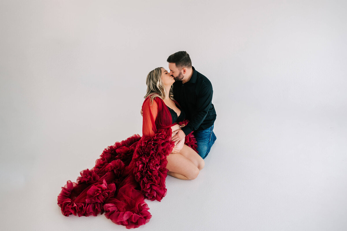 maternity pictures in Joplin MO of pregnant couple kneeling on ground kissing