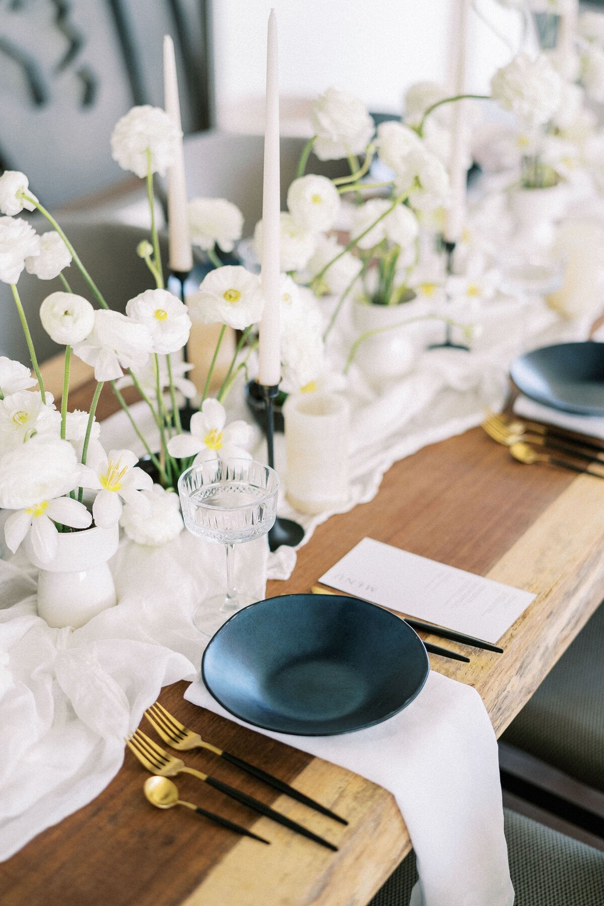 menus-lie-near-black-plates-festive-table-with-white-flowers-narrow-tablecloth