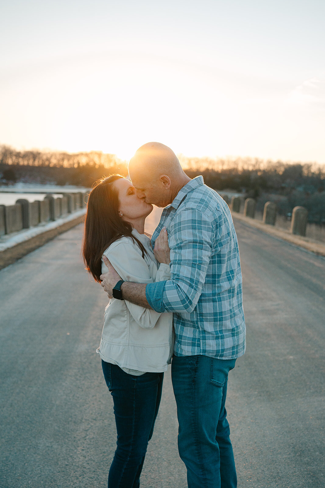 A couple kissing in the middle of a road at sunset 