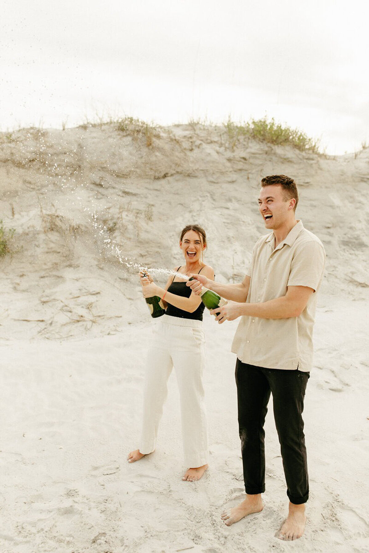 Popping champagne on beach taken by engagement photographer in orlando