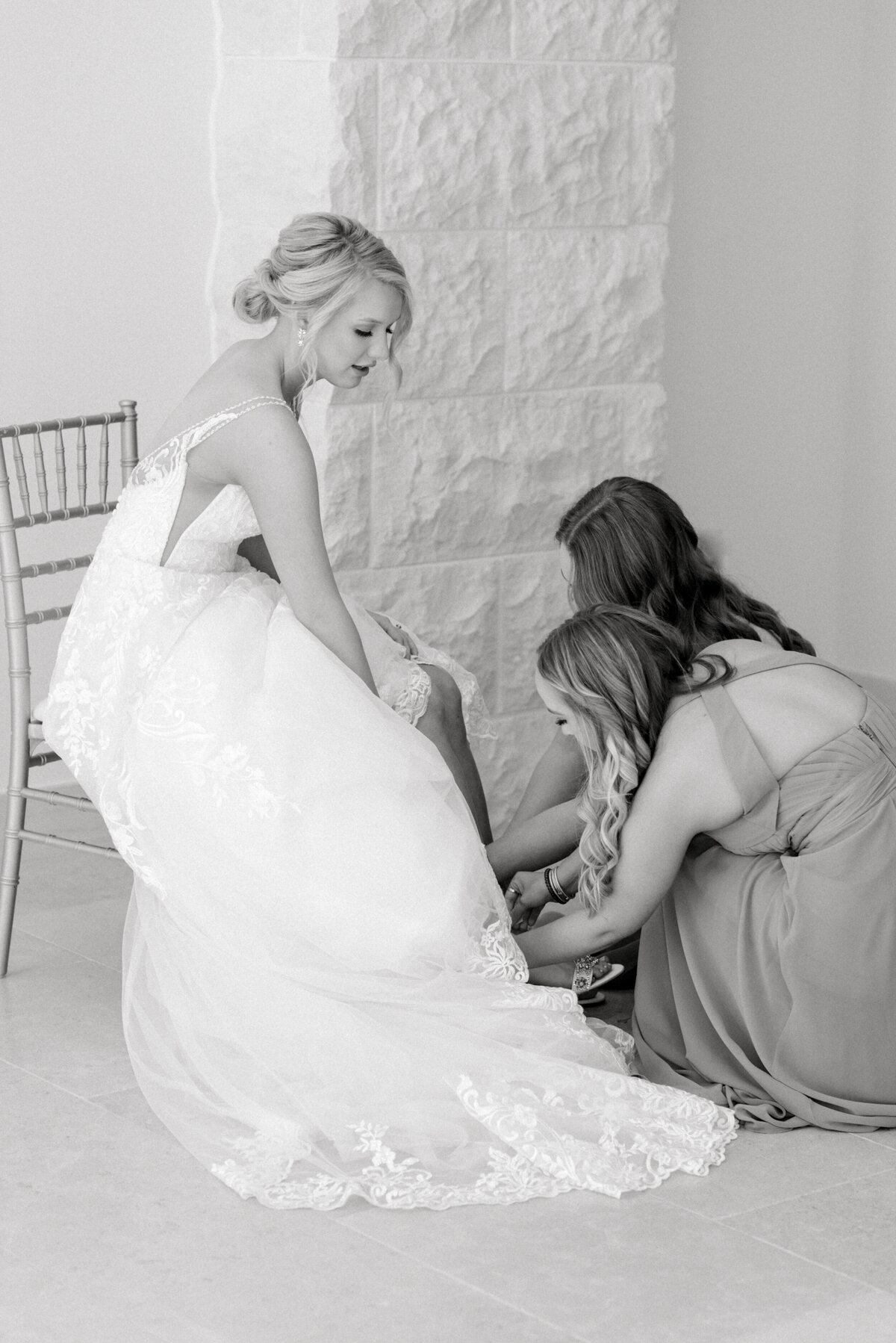 bridesmaid helping bride with her shoes