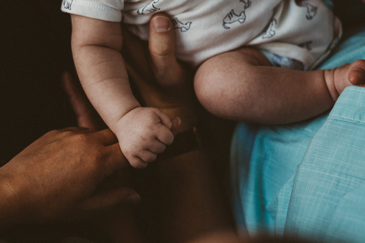 details of baby legs, arms as being held by his parent