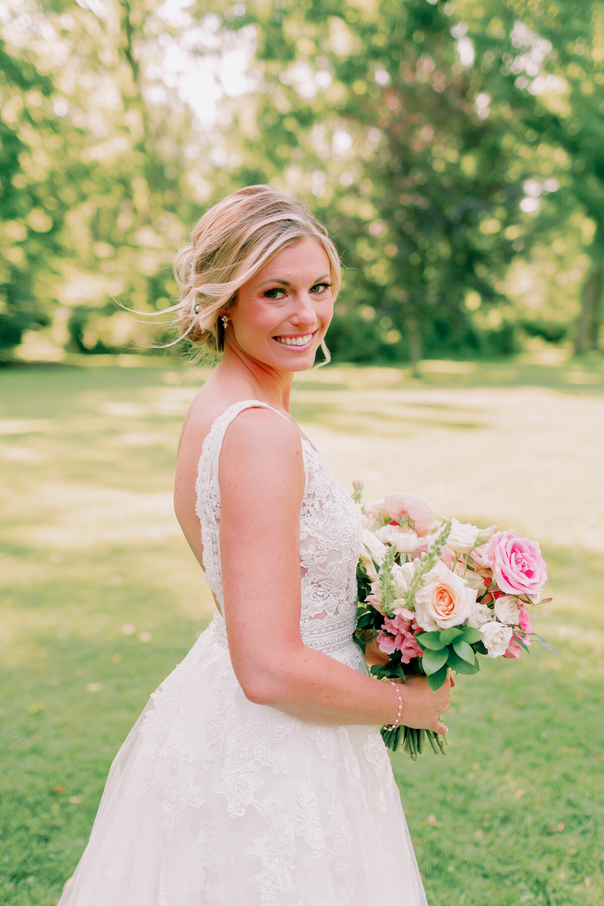 A person in a wedding dress smiling and holding a bouquet of flowers 