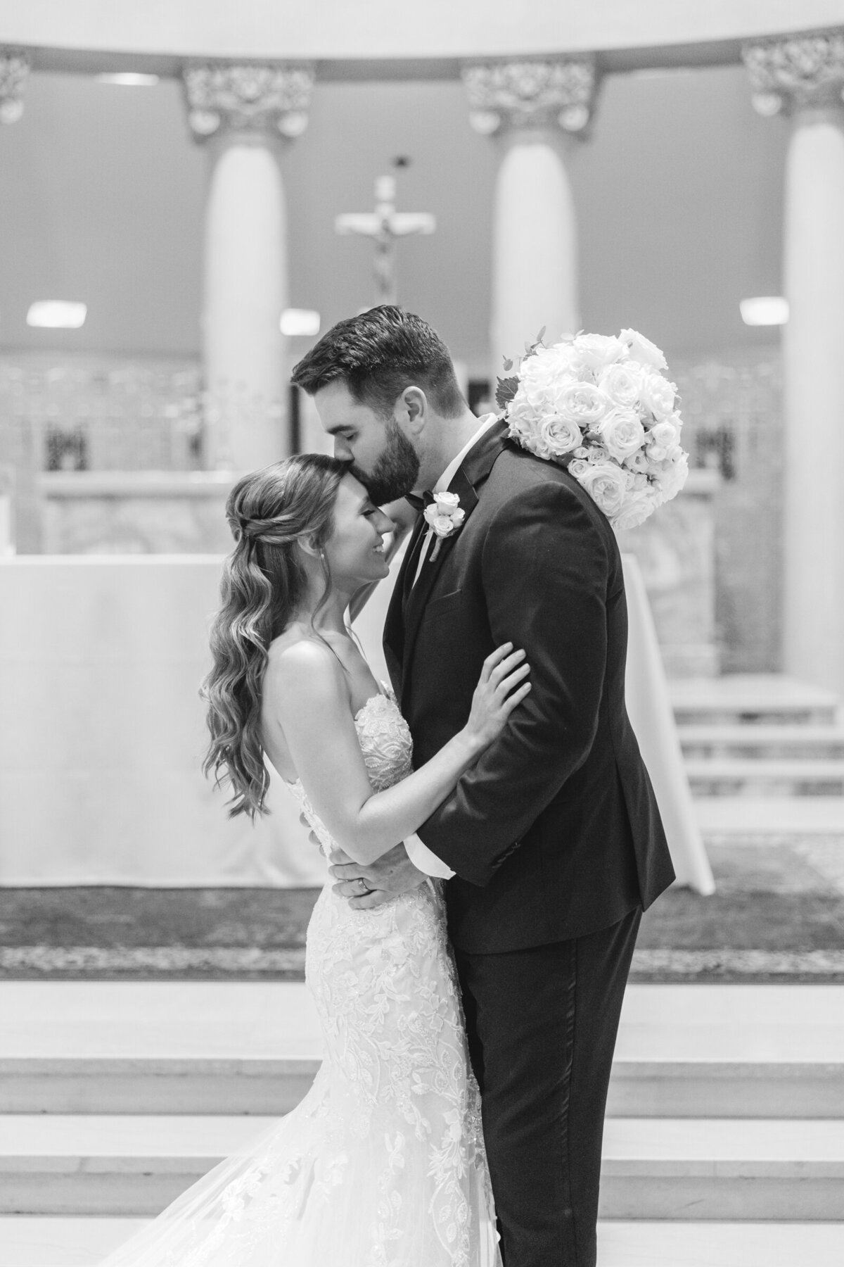 A groom kisses his new wife on the forehead