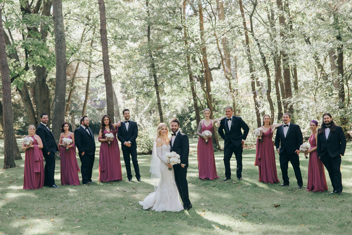 Luxurious bride and groom surrounded by their glamorous bridal party during outdoor portraits