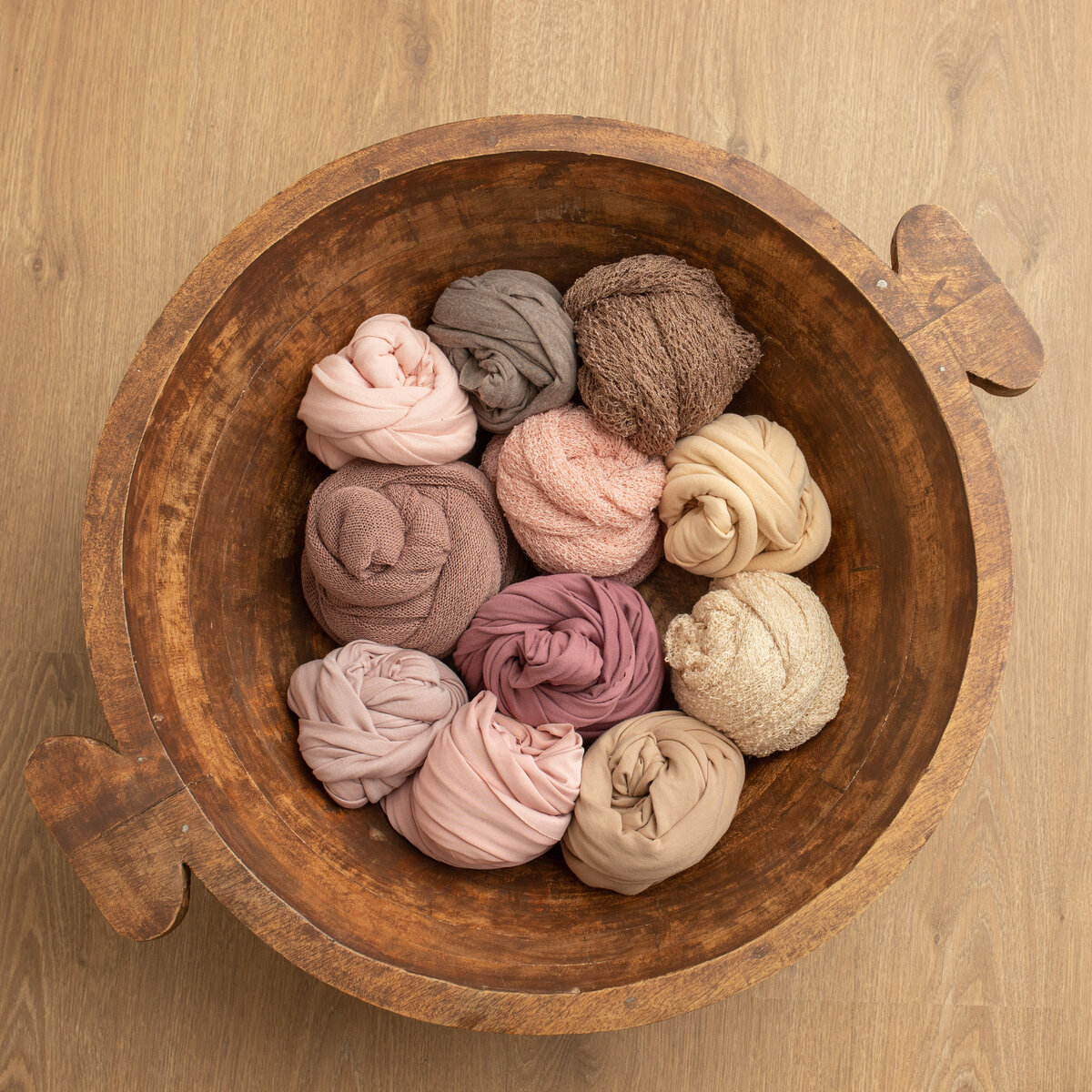 The image depicts a prop bowl with a number of pink toned wraps for newborn photography.  Studio sample image by Lauren Vanier Phtoography