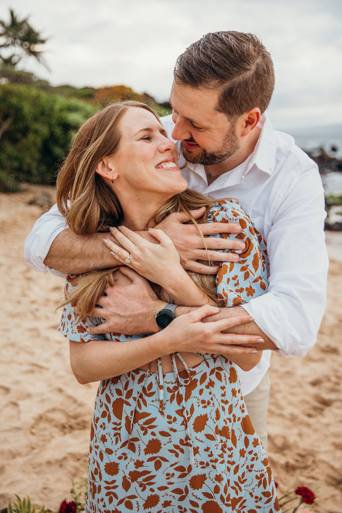 Hawaii Engagement Photographer captures man wrapping arms around woman at beach engagements photos