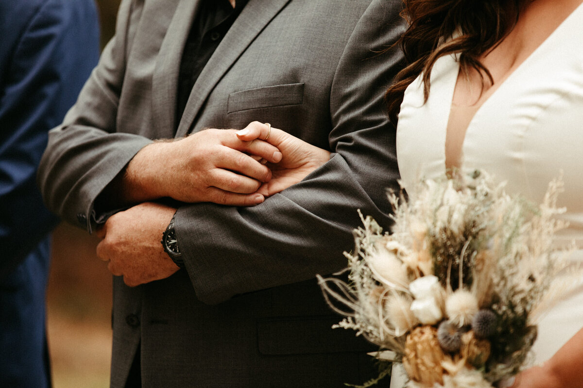 Close up of bride and her dad holding hands as he hands off his daughter during the ceremony