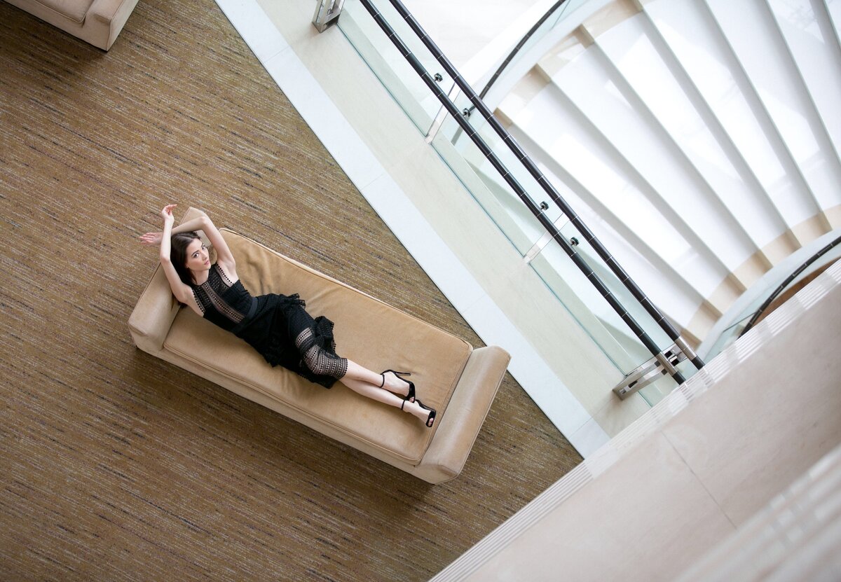 Image of woman lying on a couch in a black dress