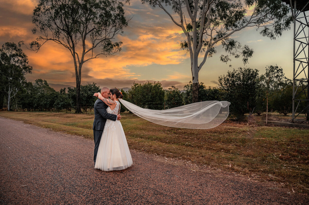 bride and groom embracing on country road embracing for a kiss - Townsville Wedding Photography by Jamie Simmons