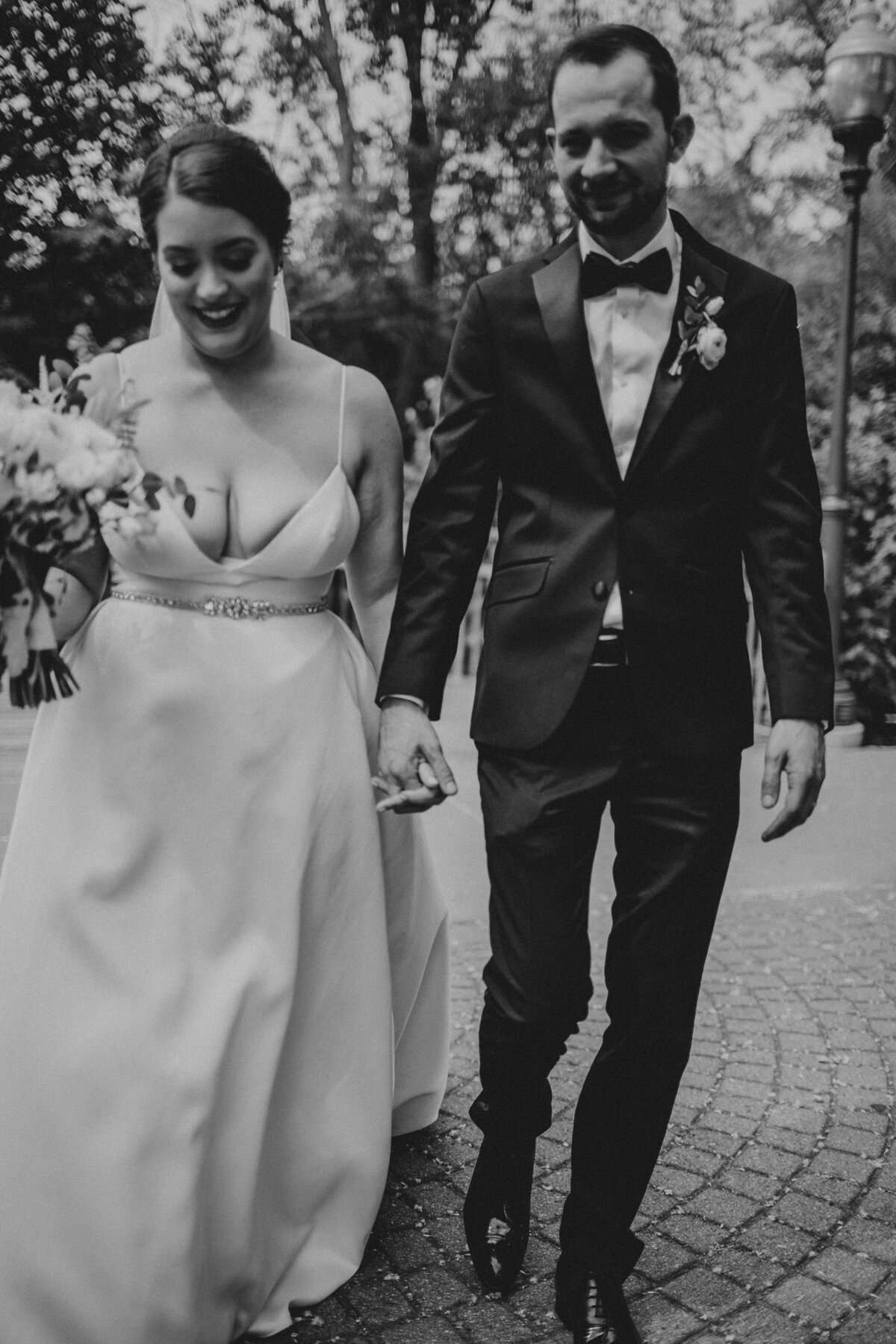 newlywed couple holding hands walking in black and white