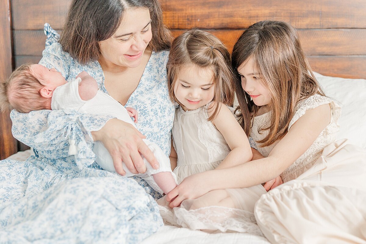 mom with kids on bed dung in-home newborn photo session with Sara Sniderman Photography in Needham Massachusetts