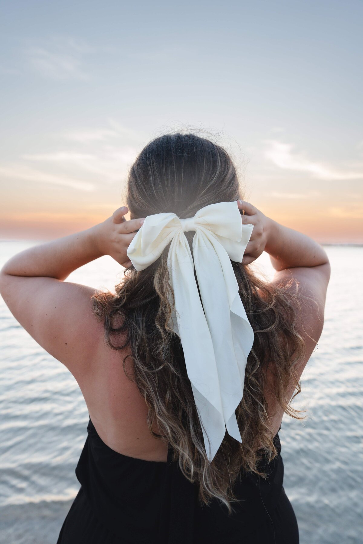 Newborn stretching  her arms and wearing a flower headband.