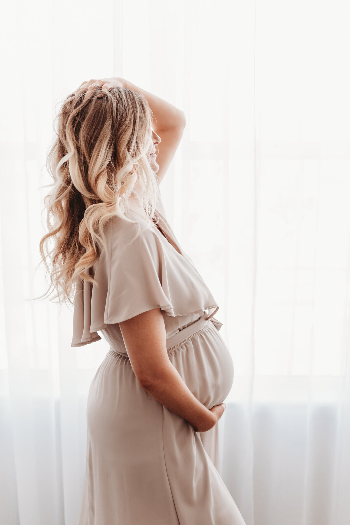 blonde woman holding her pregnant belly