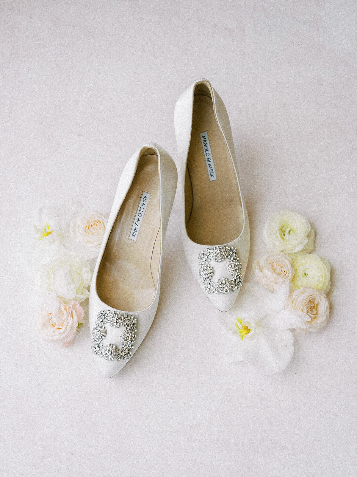 Designer shoes during a San Luis Obispo wedding with white roses surrounding them