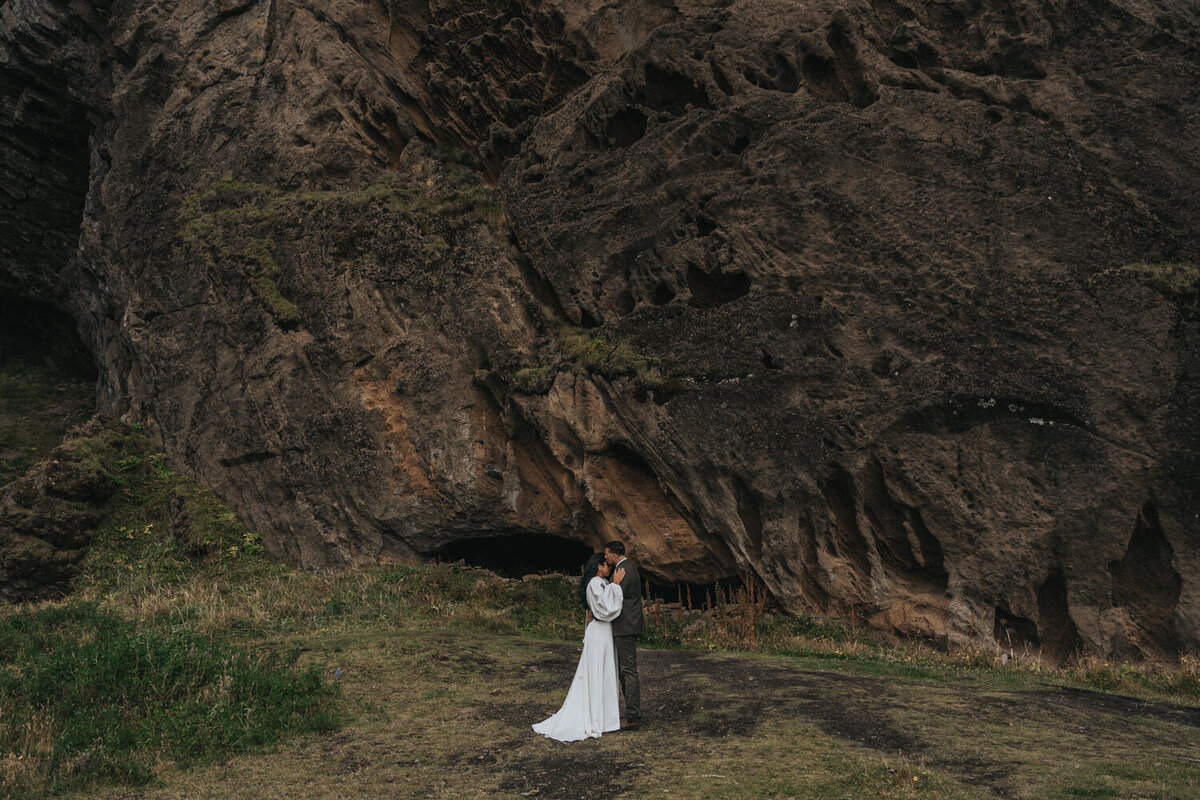 Husband and wife stand forehead to forehead in front of a Iceland mountain 