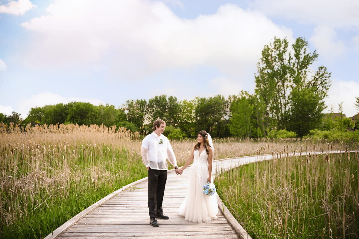 Wedding couple walking hand-in-hand on wooden boardwalk