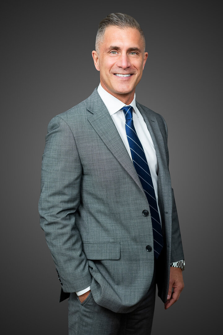 Executive headshot of professional man in gray suit and blue striped tie against neutral background, NJ corporate portrait by Alex Kaplan Photo