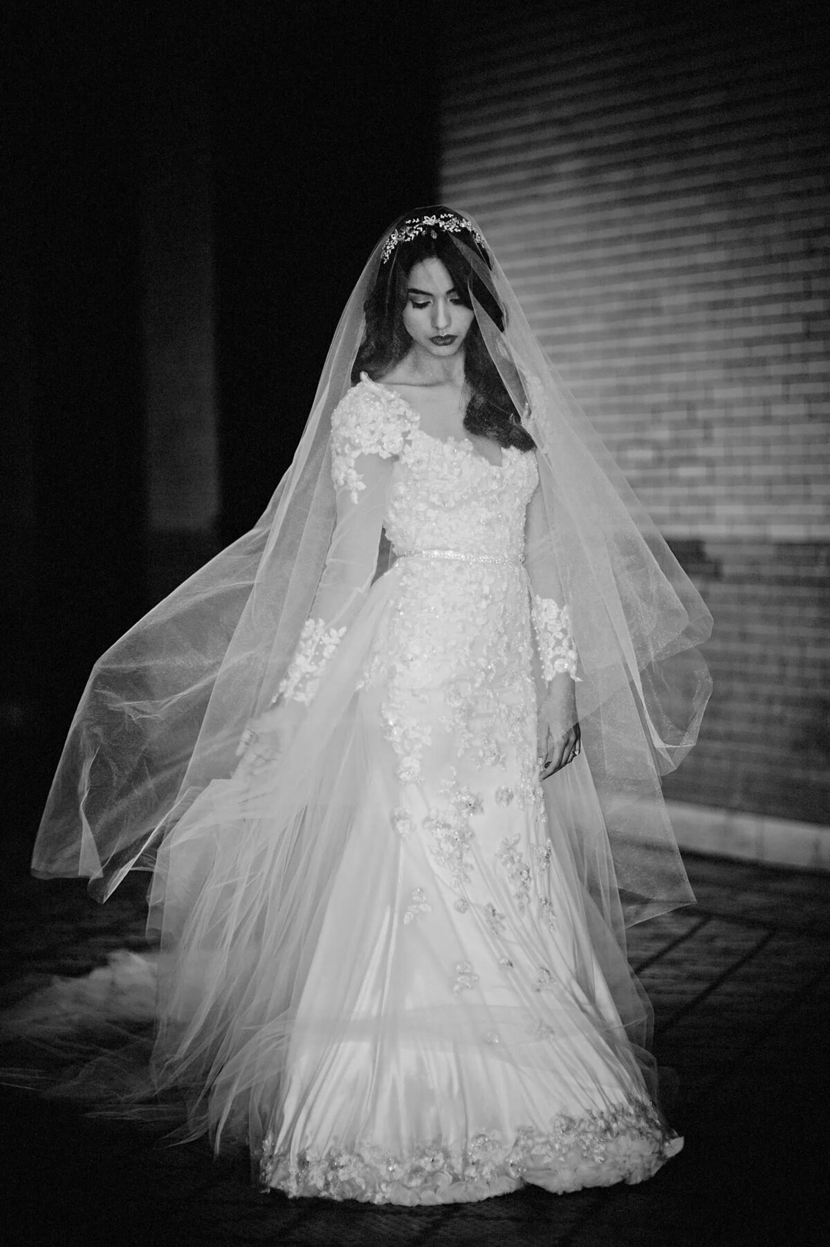 A black and white portrait of a bride in her wedding dress and veil
