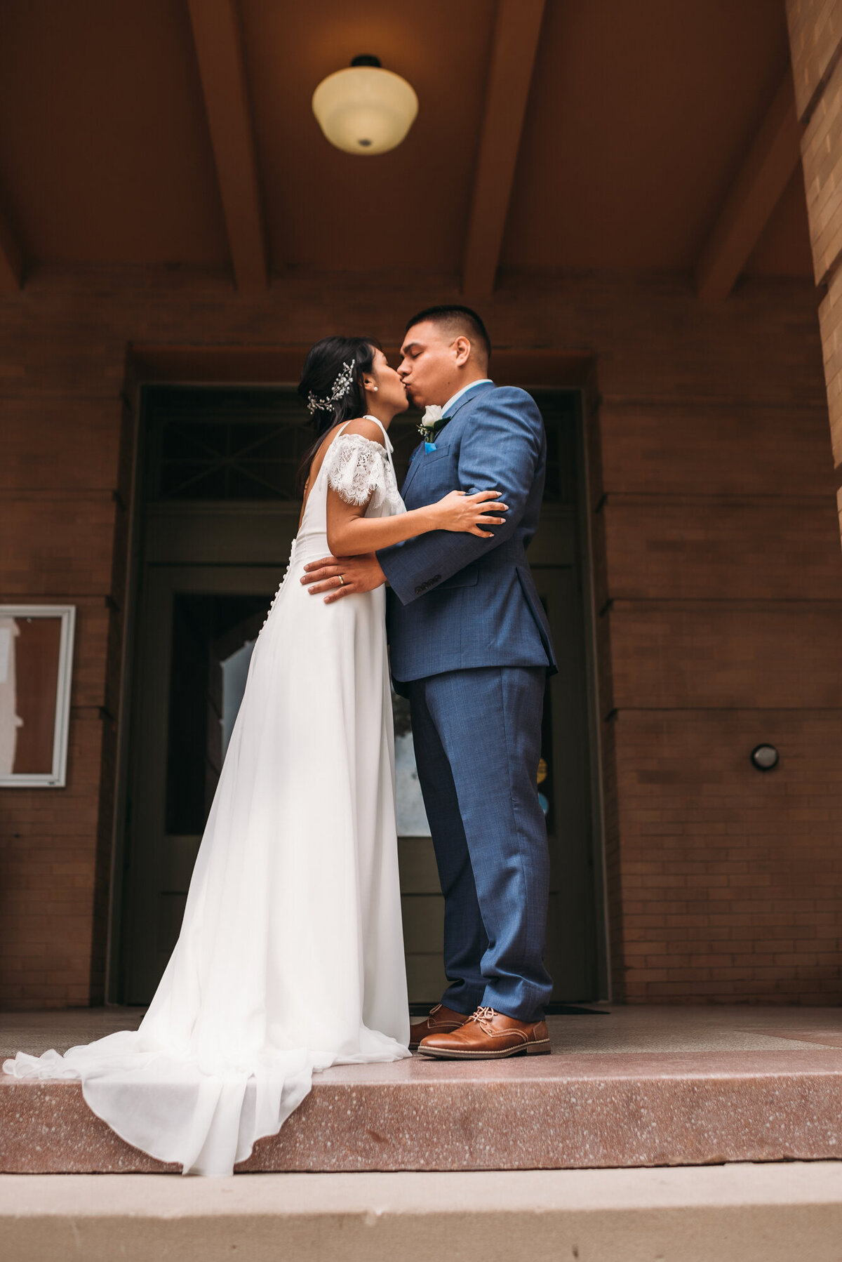 Couples Photography, a bride and groom stand outside town hall building and kiss after being married