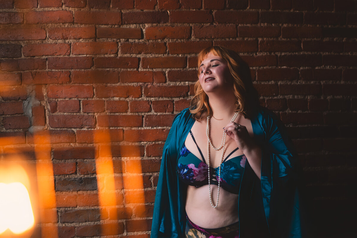 Beautiful woman with red hair wearing a blue silk robe for her boudoir session nashville