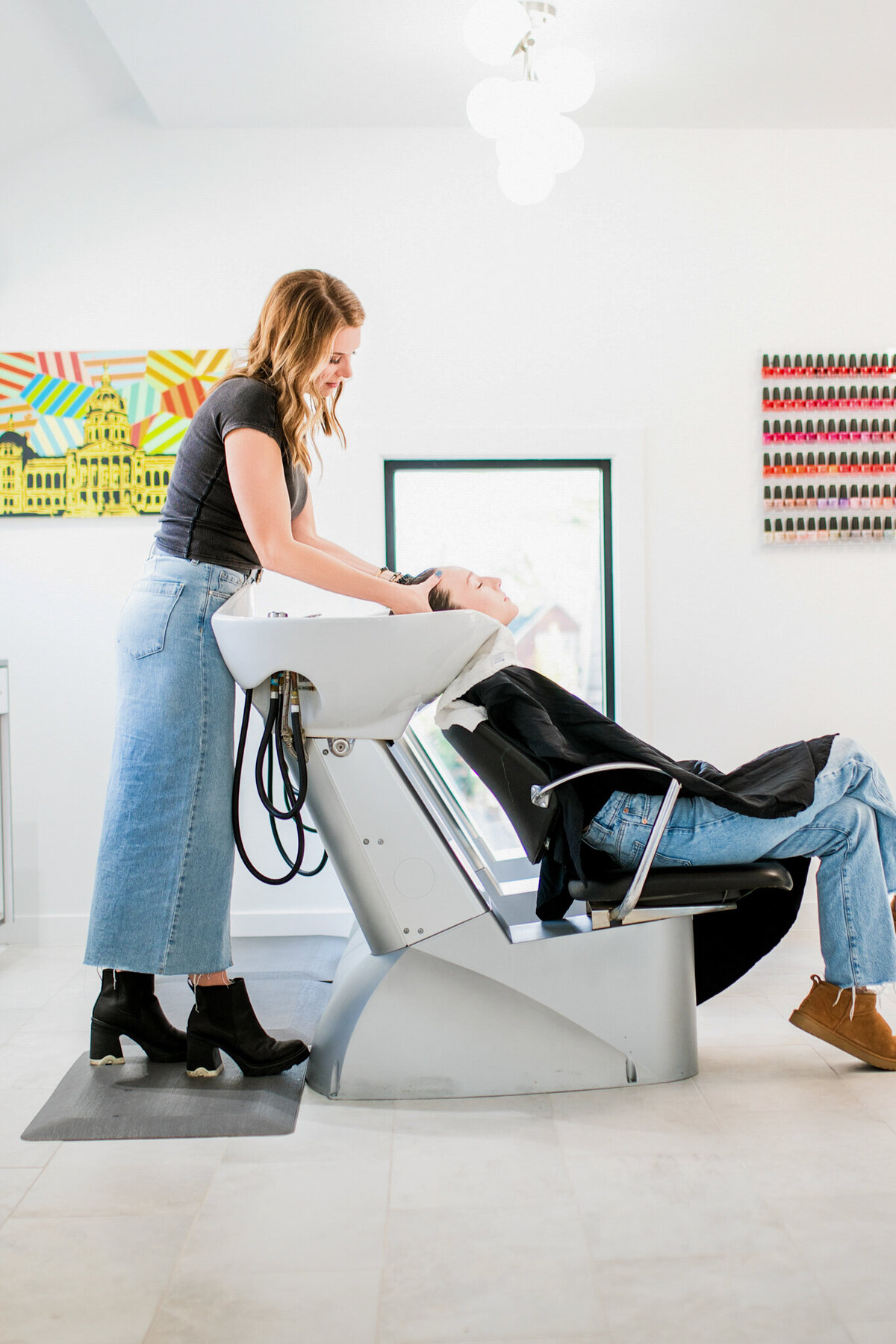 A client enjoys a moment of relaxation at a salon’s modern wash station. This shot captures the luxurious, spa-like experience that comes with a premium hair appointment.