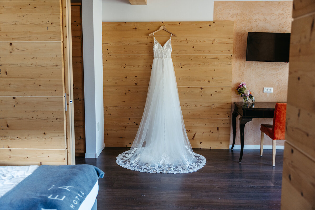 Wedding dress hanging in wooden hotel room