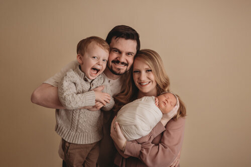Baby girl sleeping for newborn portrait session with Atlanta Georgia newborn photographer snuggled up in a swaddle posing with her family