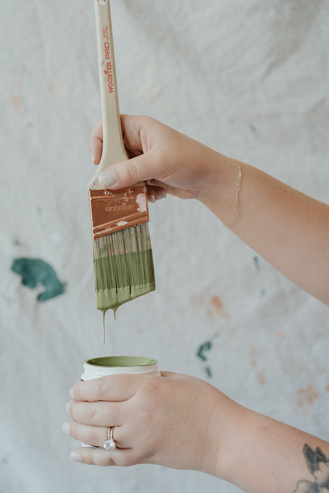 Close-up photo of a hand holding a dripping paintbrush over a paint can during a Wildher and Co branding session in Kalamazoo Michigan.