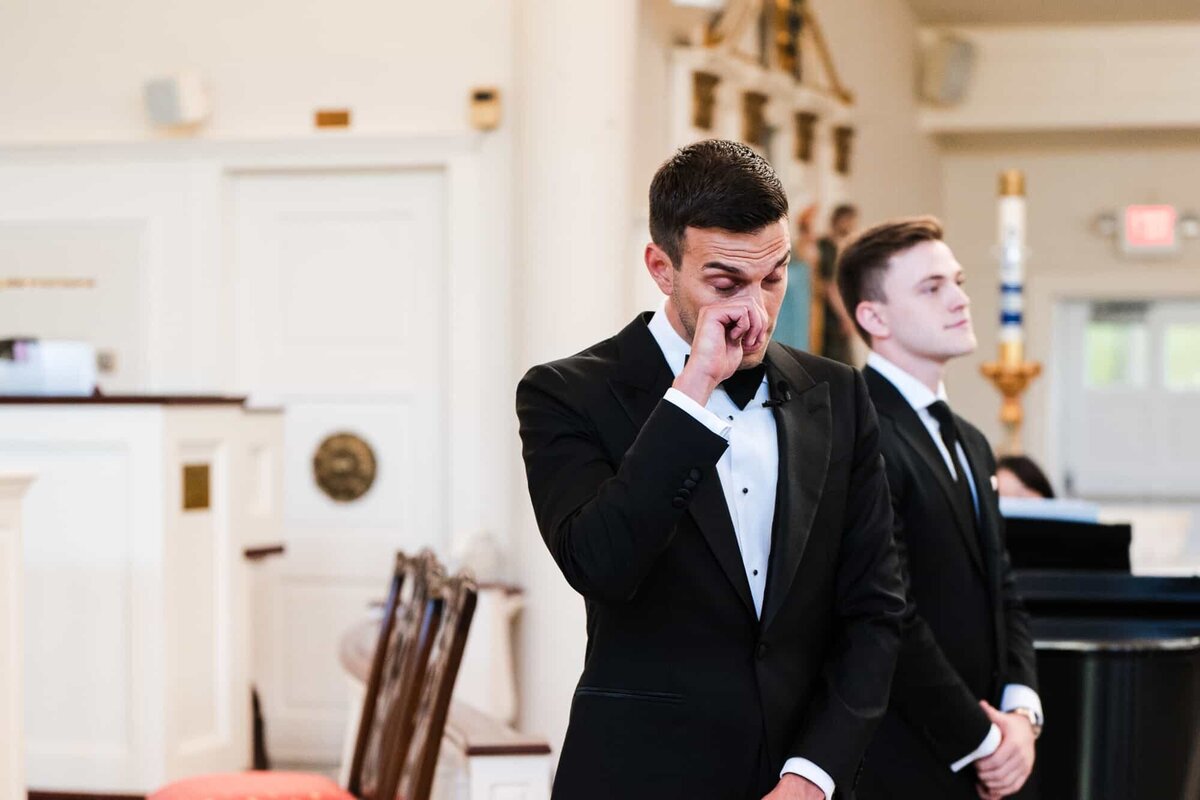 Groom wiping tear at the beginning of the wedding ceremony when he sees his bride walking down the aisle captured by Palm Beach Wedding photographer