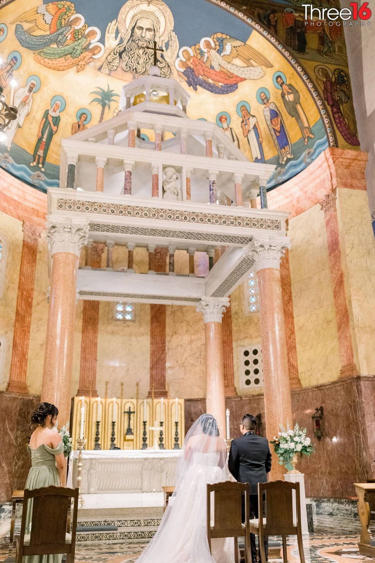 Bride and Groom stand before the altar in a Catholic church