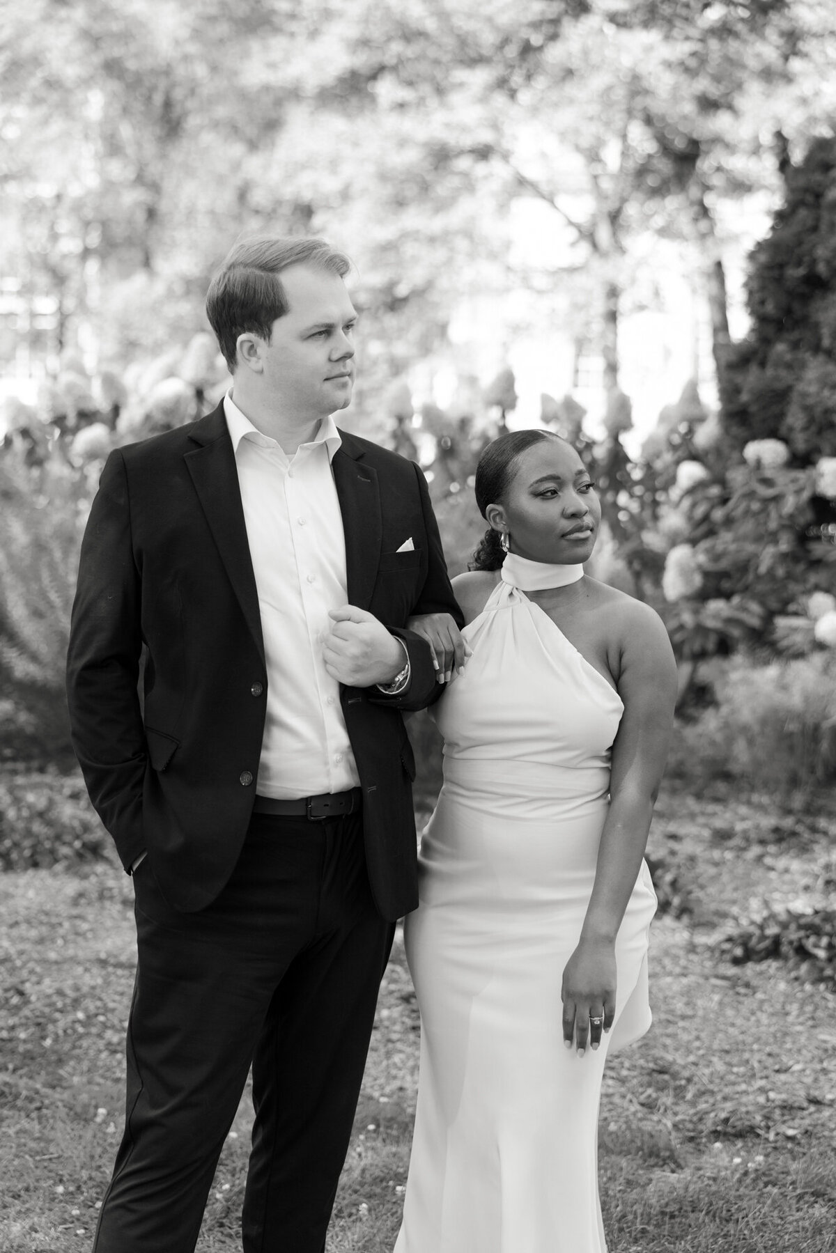 A striking black and white engagement portrait of a couple in the formal gardens along Michigan Avenue, highlighting their love with moody and elegant lighting.