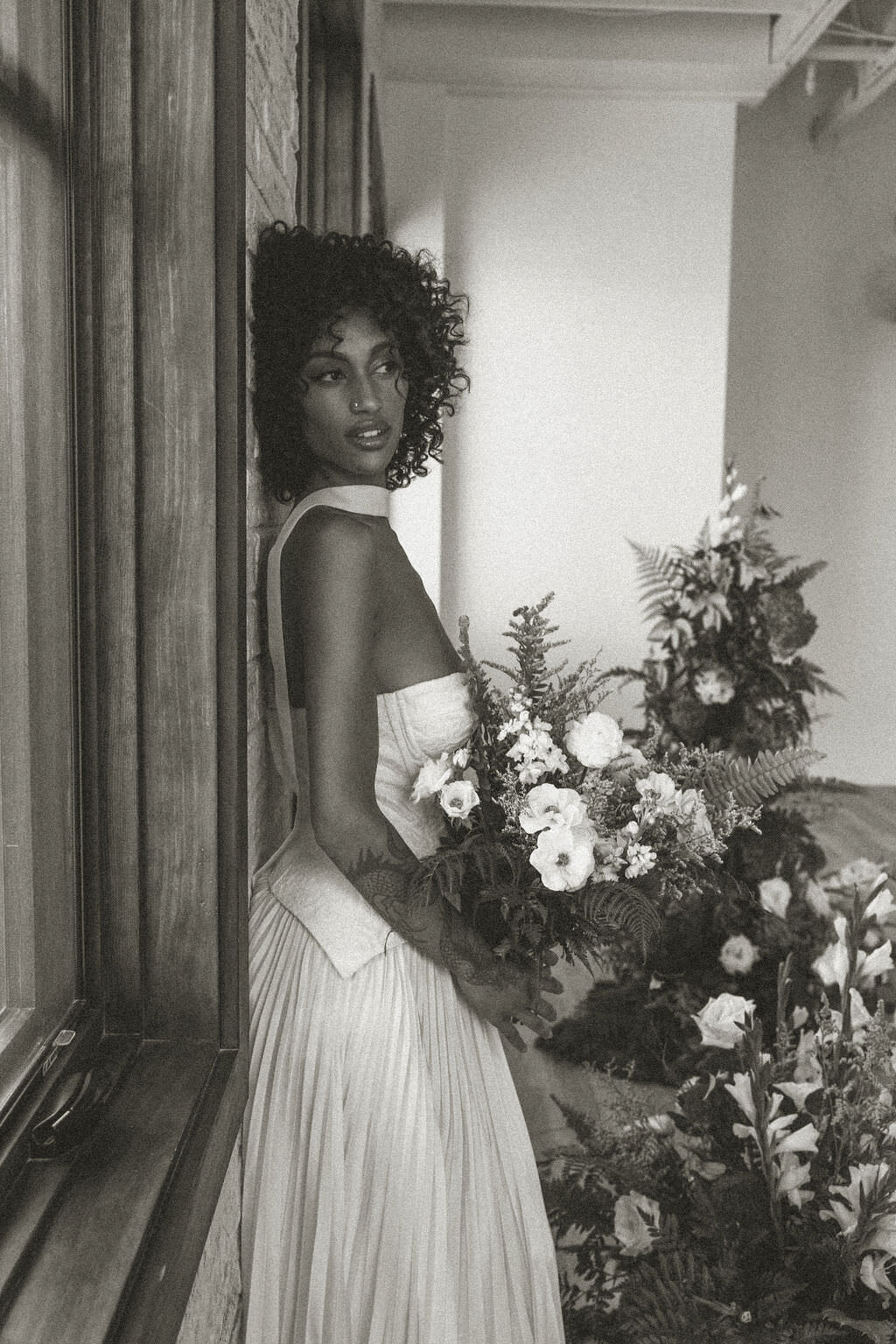 A person leaning up against a wall holding a bouquet of flowers