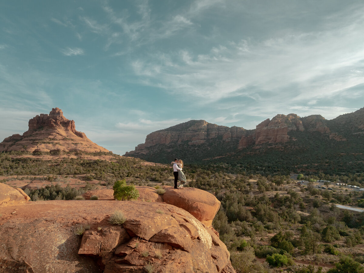 Couple standing against red rock backdrop during Sedona engagement session
