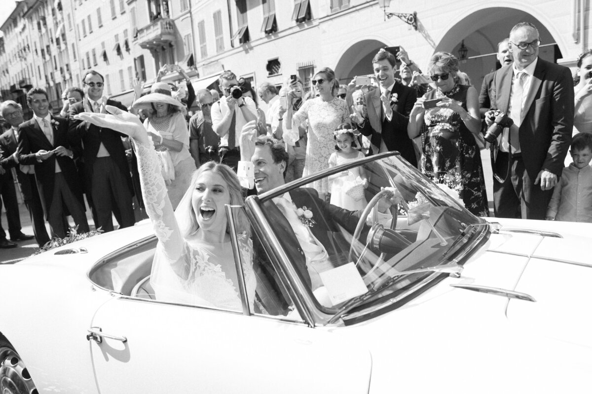 candid wedding photo of bride and groom driving through Miami in a classic car
