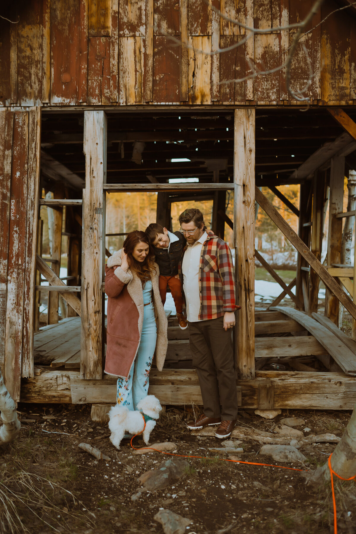 Mom and dad propped up their boy on an abandoned cabin's window frame as they all embrace each other