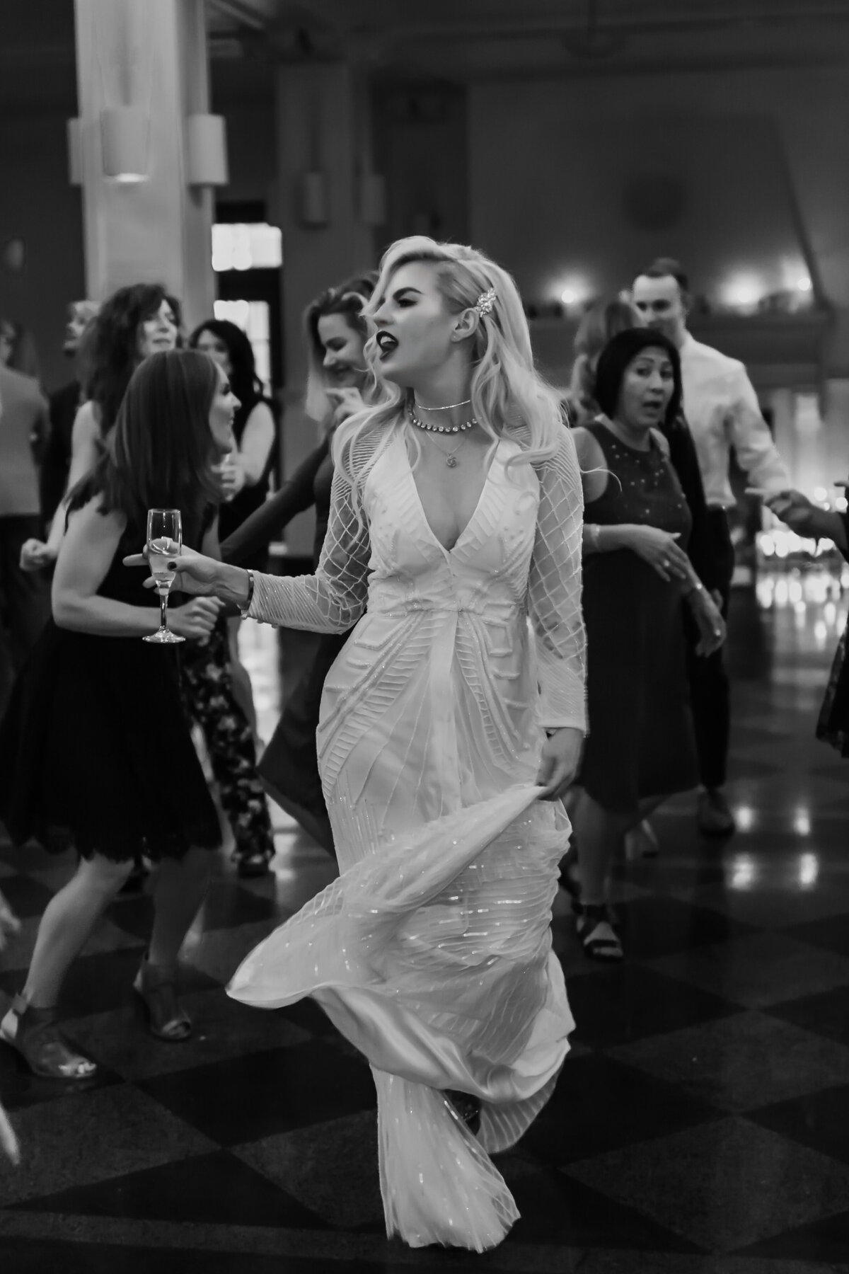 Candid moment of a bride dancing with champagne in her hand captured by Fort Worth wedding photographer, Megan Christine Studio