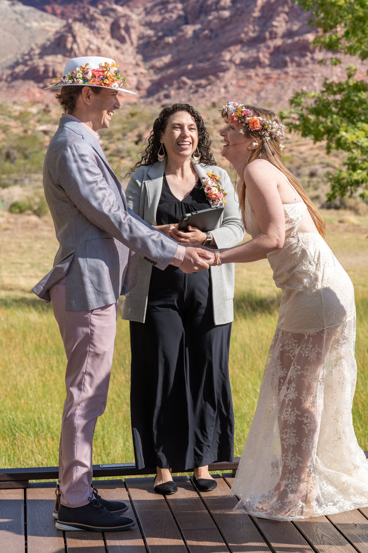 A person laughing as they hold their partner's hands during their wedding