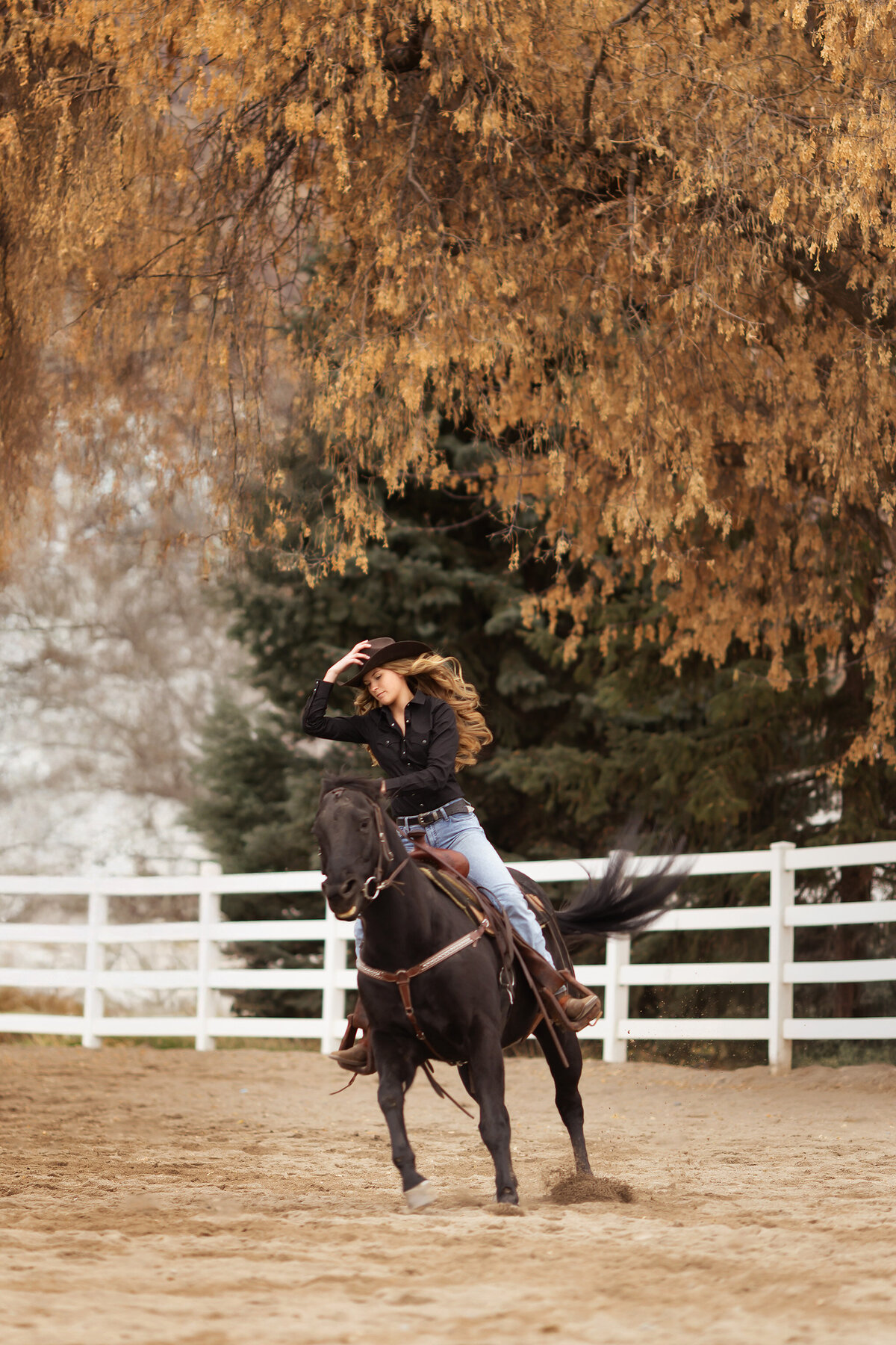 A senior girl rides her horse outdoors, captured in her jeans and cowboy hat, as seen by a Dallas senior photographer.
