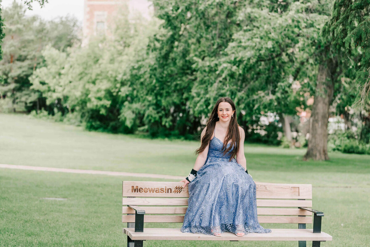 A young lady sitting on the top of a bench. 