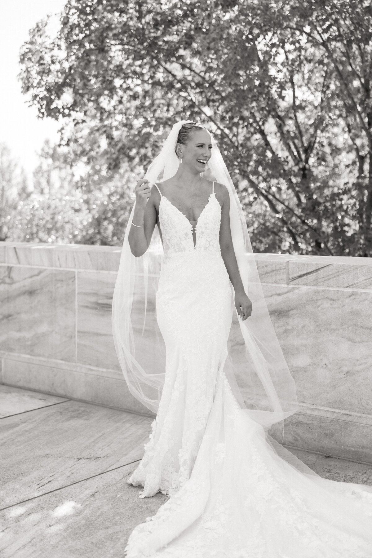 Black-and-white shot of joyful bride laughing with her veil flowing, captured by a Philadelphia wedding photographer.