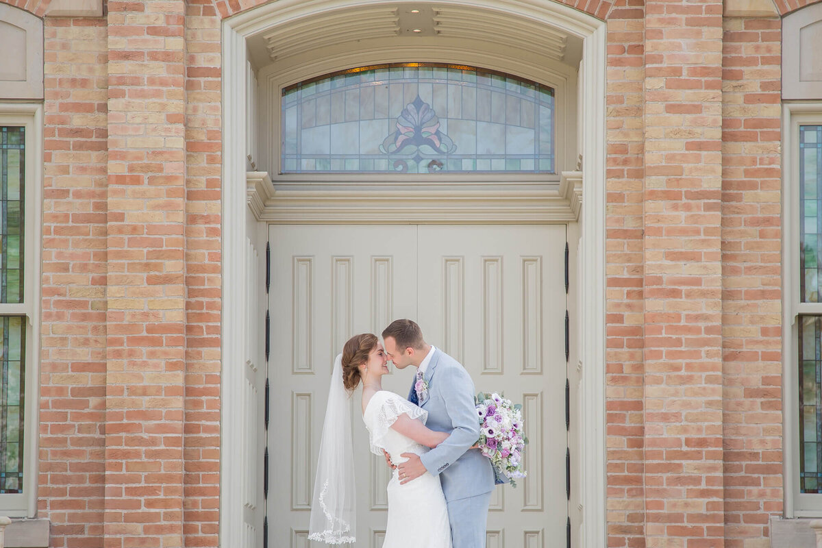 bride and groom kissing in front of a brick building