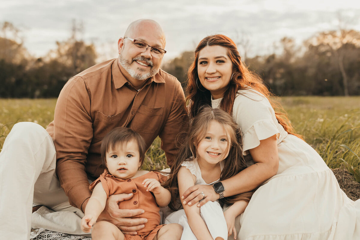 family of 4 sits on a blanket